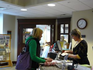 Library staff member checking out book to user